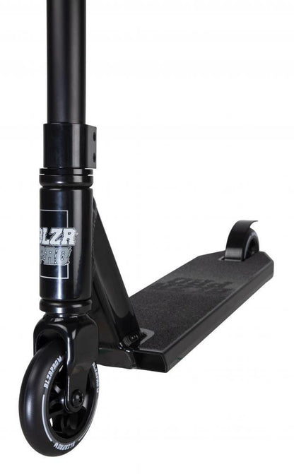 Close-up of the Blazer Pro Shift Mini Complete Stunt Scooter in black, highlighting its lightweight aluminum deck with textured grip tape. It features a metallic brake on the rear wheel and a sleek front wheel connected to the handlebar stem. Perfect for freestyle scootering, the Blazer Pro logo is prominently displayed on the front deck.