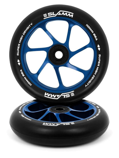 The Slamm Team 110mm Stunt Scooter Wheels by Slamm come in black and blue, featuring a white "SLAMM" logo and are marked with "Super High Density, 110mm, 88A." These wheels sport an aluminium core with a spoked design, displayed stacked with one standing upright and the other laid on its side.