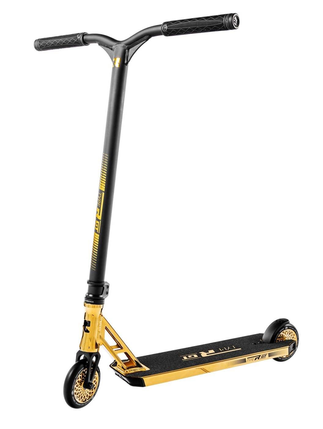 The Root Industries Type R GT Complete Stunt Scooter - Gold Rush elegantly combines a black and gold design with a textured deck featuring gold accents and dual black wheels. It offers wide handlebars with grips for enhanced control, standing upright on one wheel as a testament to the stylish precision characteristic of Root Industries scooters.