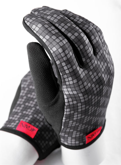 The GAIN Protection Resistance Skate Gloves - Logo by GAIN feature a stylish black design with a gray checkered pattern on the back made from ARMORTEX fabric. These gloves include a black palm, red tags near the wrist, and are touchscreen compatible. Set against a white background, they highlight their sleek and functional design.