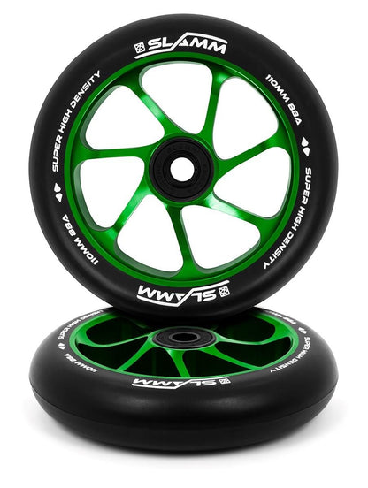 Two Slamm Team 110mm Stunt Scooter Wheels, featuring a black and green five-spoke design, are stacked. They boast high-rebound PU for superior performance and green rims with a high-density label. The aluminium core enhances durability, while the "SLAMM" brand name is prominently displayed across both wheels.