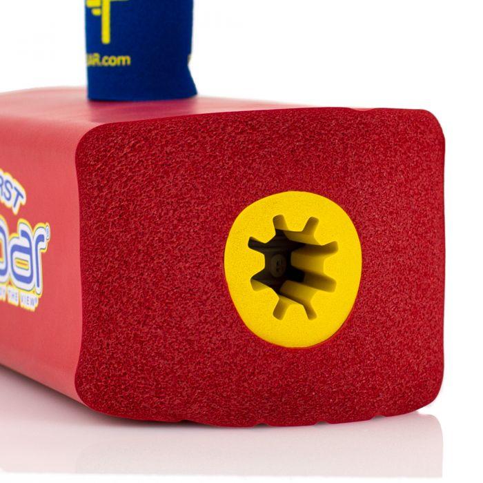 Close-up of a square red foam pool noodle featuring a yellow star-shaped hole in the center, similar to the design on the Flybar My First Foam Pogo Jumper. In the background, a portion of blue and yellow lettering can be seen on the foam surface.