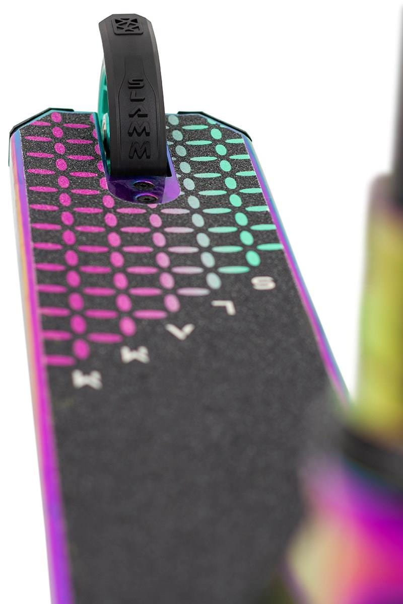 Close-up of the vibrant alloy deck on the Slamm Assault Complete Stunt Scooter - Neochrome, showcasing a multicolor pattern with dots and lines. The grip tape bears partial branding and links to a black fender. Its metallic, reflective finish harmonizes seamlessly with the 110mm aluminum wheels.