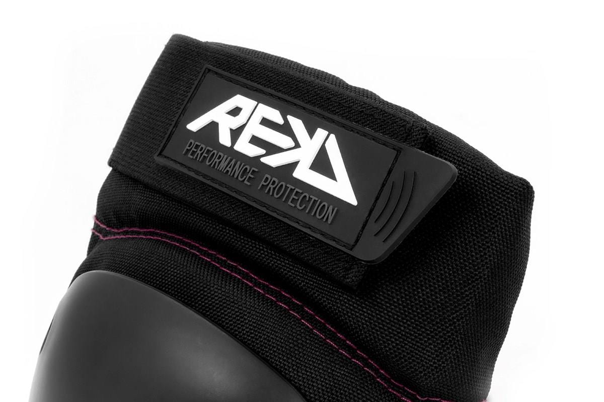 Close-up of the REKD Ramp Knee Skate Protection Pads in Black/Pink, crafted for action sports enthusiasts. Highlighting the "REKD" brand logo and "Performance Protection," these pads boast a hard protective surface with pink stitching, providing impact resistance for those who prioritize safety and style.