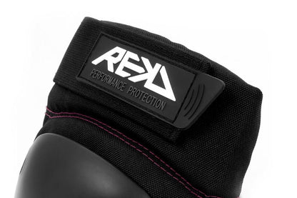 Close-up of the REKD Ramp Knee Skate Protection Pads in Black/Pink, crafted for action sports enthusiasts. Highlighting the "REKD" brand logo and "Performance Protection," these pads boast a hard protective surface with pink stitching, providing impact resistance for those who prioritize safety and style.