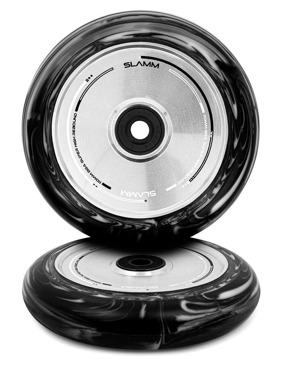 Two Slamm Swirl 110mm Stunt Scooter Wheels, in a sophisticated black and silver design, are stacked vertically. The brand name "Slamm" is prominently displayed on the metal core. These wheels feature ABEC-9 Chrome bearings and boast a Duo-Tone Split Swirl Effect Urethane. One wheel is positioned upright while the other rests flat.