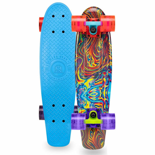 Two skateboards are displayed. The left skateboard, the Madd Gear MGP G-Retro Oil Slick Complete Cruiser, showcases a solid blue deck with embossed branding. The right skateboard features a vibrant, swirling multicolor pattern. Both ensure a smooth ride with colorful, translucent wheels in shades of pink, purple, orange, and neon green.