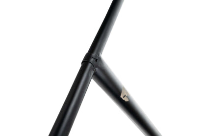 A close-up view showcases a black chromoly metal frame with a joint creating an angular intersection. Against a white background, this emphasizes the robust and sleek design, possibly belonging to the Supremacy Trojan Steel Standard SCS Stunt Scooter T-Bars - Black 710mm x 610mm or another larger assembly.