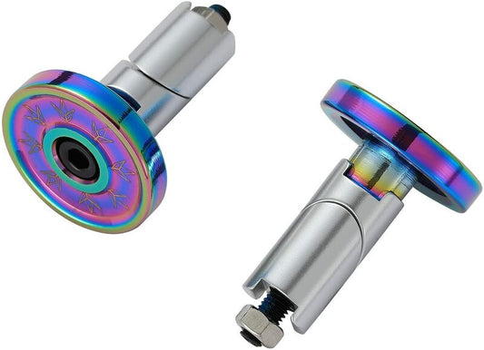 The image depicts two Blunt Envy Alloy Scooter Bar Ends in Oil Slick Neochrome. These metallic bar ends feature an iridescent star pattern, with cylindrical bases in silver and colorful, rainbow-hued circular tops. Designed with an expandable feature, they fit a range of scooter bars. One bar end stands upright while the other is positioned on its side, revealing a bolt.