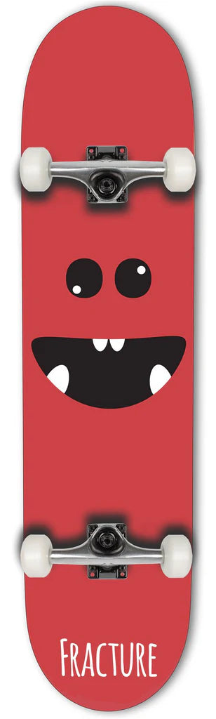 The Fracture Lil Monster Red Mini Complete Skateboard, measuring 7.25" x 28.9", showcases a cartoon face design with a big, smiling mouth and eyes. The word "Fracture" appears at the bottom of the deck. As part of the Lil Monsters series, this skateboard includes white wheels and metal trucks.