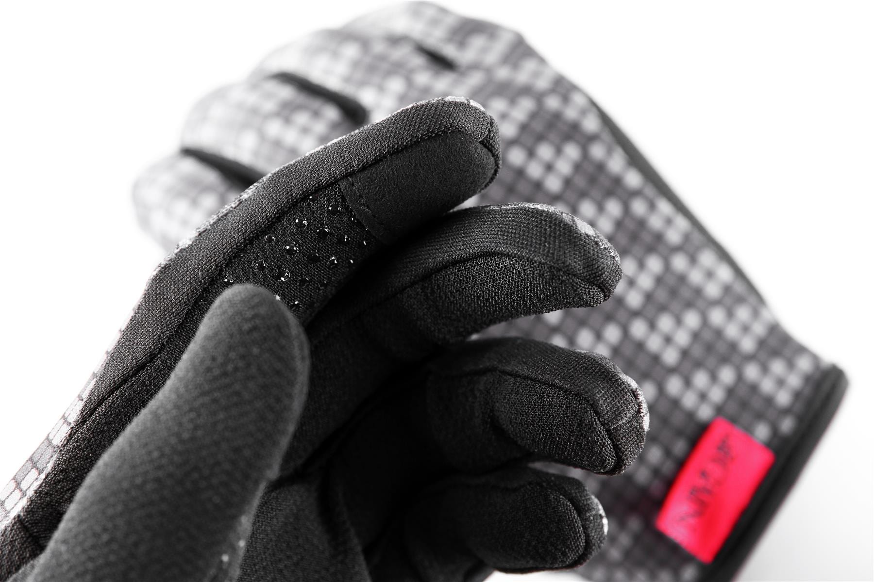 Close-up of the GAIN Protection Resistance Skate Gloves - Logo, showcasing a pair of gray gloves with a red label and black textured grip on the fingers. These soft, insulated gloves feature a checkered pattern, ARMORTEX fabric, and touchscreen compatibility, providing warmth and comfort for cold weather.