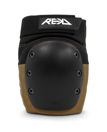 A close-up of the REKD Ramp Knee Skate Protection Pads in Black/Khaki, showcasing a hard black shell adorned with multiple rivets. The top displays "REKD" ensuring impact resistance and high durability for all your adventurous pursuits.