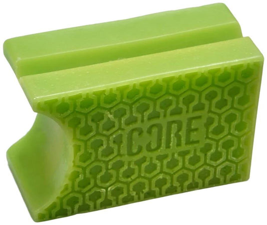 An apple green, rectangular item with a grid-like surface texture and the engraving "CORE Epic Skate Wax" is designed by CORE. It includes a curved cut-out on one side, resembling a clamp or holder, making it an ideal secret slide compound for skateboarders.