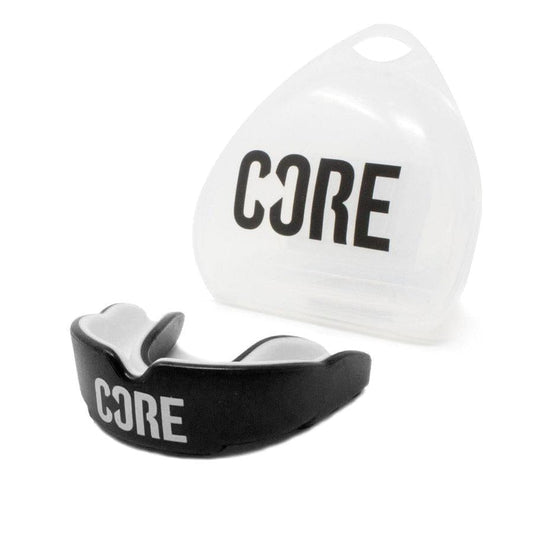 A black and gray CORE Skate Protection Mouthguard, emblazoned with the brand name "CORE," is presented next to its transparent carrying case, which also displays the "CORE" logo. This impact-absorbing gum shield offers premium protection and fits snugly in its upright case, making it perfect for skate protection enthusiasts.