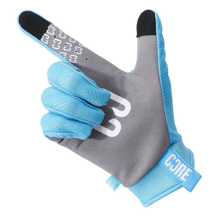 A single teal CORE Aero Skate Protection Glove features the word "CORE" on the wrist. It is designed in a shape resembling a hand forming a "gun" gesture, with the index finger extended and thumb up, while other fingers are folded down. Additionally, it boasts a Skin Fit design and is touch screen friendly for added convenience.