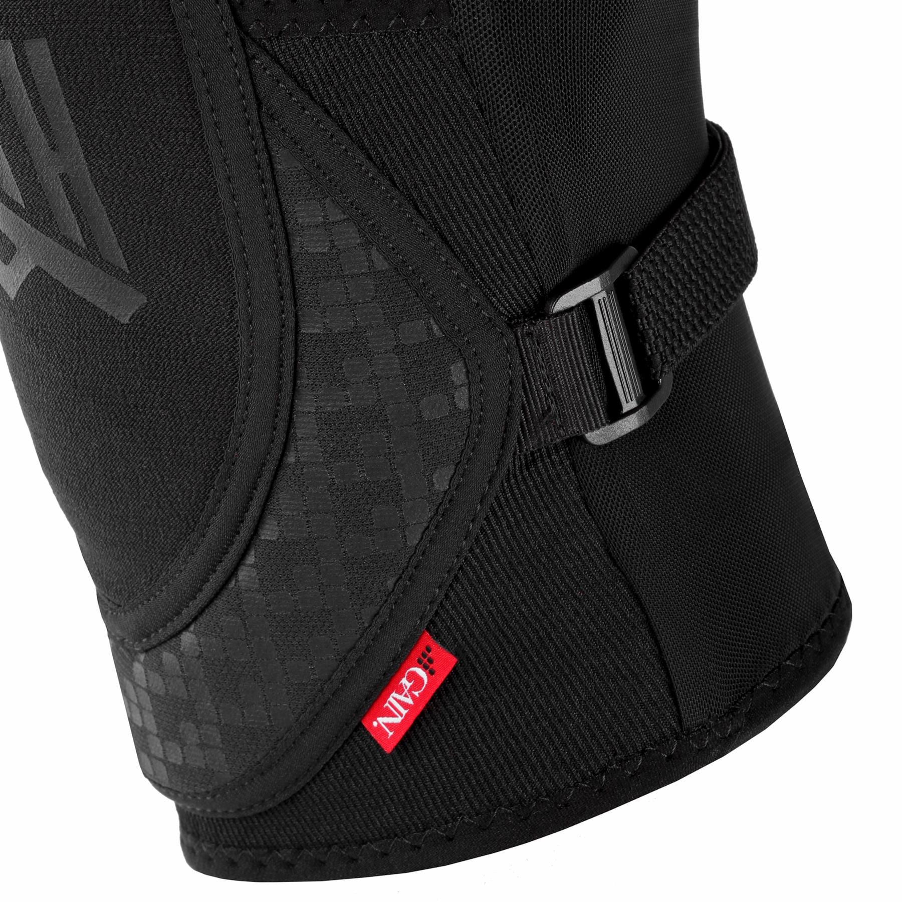 Close-up of a black GAIN Protection Stealth Knee Skate Pad showcasing a textured design, adjustable strap, metal buckle, and a small red tag with the "G-Form" logo near the bottom edge. Made with DuraTec neoprene, the material looks robust and protective.