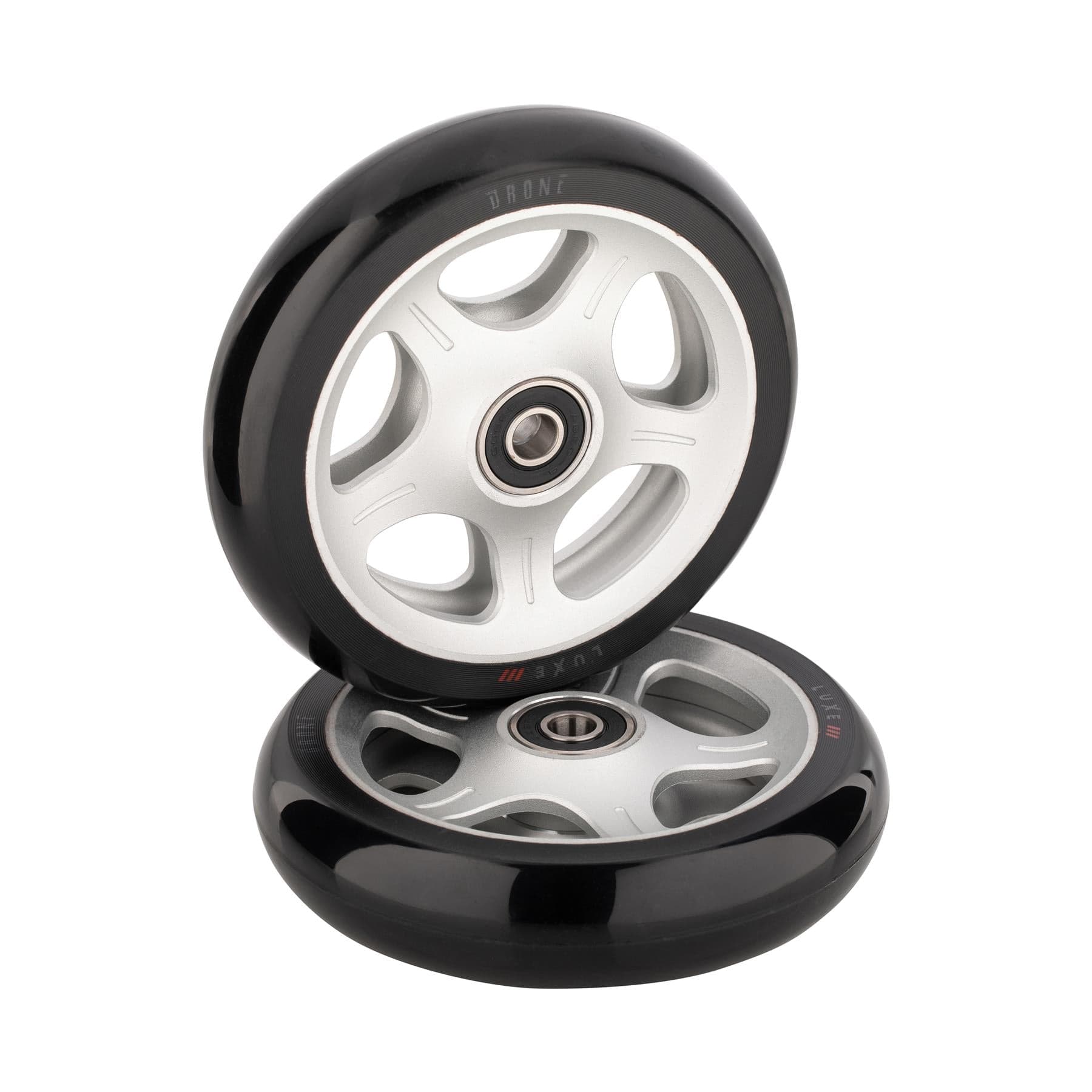 Two silver Drone Luxe 3 dual-core stunt scooter wheels, one upright and the other flat, feature multiple spokes and central bearings for optimal performance.