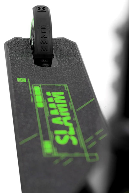 A close-up of the Slamm Classic Mini Complete Stunt Scooter - Green showcases its black deck with a single rear wheel, highlighted by vibrant neon green graphics and the bold brand name "Slamm." The image emphasizes the scooter's sleek design, perfect for freestyle scootering, against a white background.