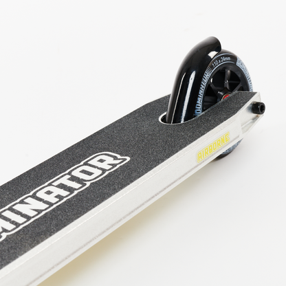 Close-up of the Dominator Airborne Complete Stunt Scooter's deck featuring a rear wheel. Perfect for riders ranging from intermediate to professional levels, its deck is made from military-grade 6061 T6 aluminum with textured black surfaces. The sleek design is highlighted by the black tire with white text accents.