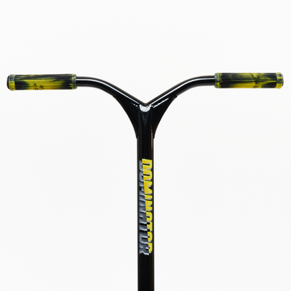 A close-up view of the Dominator Airborne Complete Stunt Scooter reveals a black handlebar adorned with vibrant yellow grips, ideal for riders ranging from intermediate to professional levels. The word "DOMINATOR" is vertically emblazoned on the stem, which is crafted from military-grade 6061 T6 aluminum. The background remains plain white.