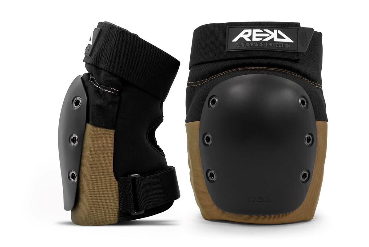 Displayed are two REKD Ramp Knee Skate Protection Pads in black and khaki, equipped with durable hard plastic caps. Ideal for action sports, these pads include adjustable straps and offer superior impact resistance. The brand "REKD" is prominently visible on the label, ensuring durability for protective use.