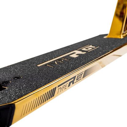 The image highlights the Root Industries Type R GT Complete Stunt Scooter in Gold Rush, showcasing a golden deck with black grip tape prominently featuring "Type R GT" in bold. It emphasizes the sleek design and branding, suggesting the inclusion of HMA Aluminium bars that enhance this high-performance scooter.