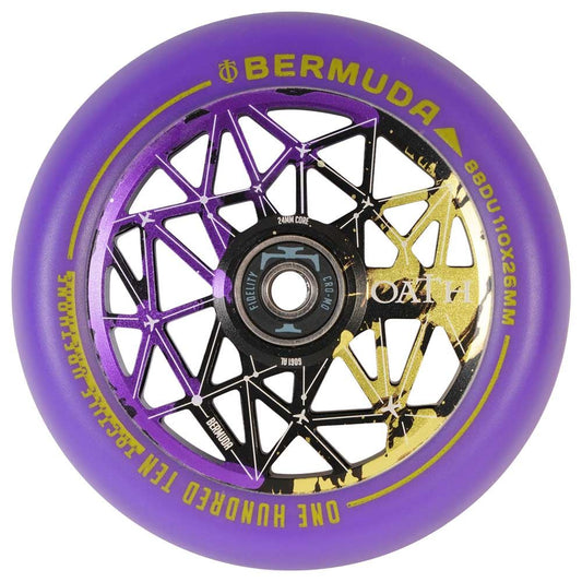 Close-up of an Oath Bermuda 110mm stunt scooter wheel in black, purple, and yellow showcases a geometric spoke pattern with high-grade bearings. The text on the wheel reads "Bermuda" and "One Hundred Ten Millimeters" in gold and white lettering.