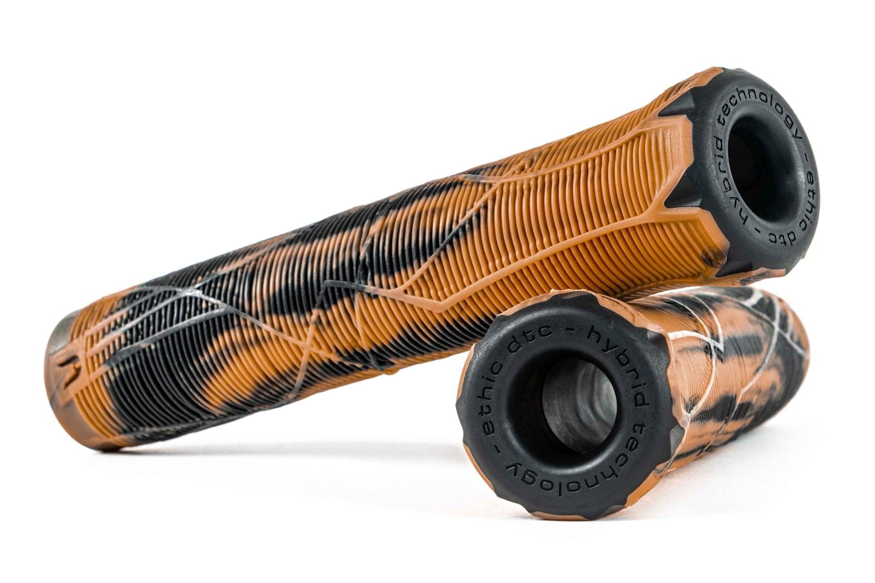 Two Ethic Slim Raw Gum/Black Stunt Scooter Grips with a signature grip pattern in orange and black camouflage feature "ethic dtc - hybrid technology" on the end caps. One grip lies horizontally, while another is balanced vertically, showcasing a sleek design.