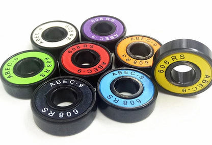 A vivid assortment of Skates.co.uk ABEC 11 Candy Skateboard Bearings is showcased on a white surface, each featuring a distinctively colored rim in shades of purple, white, red, yellow, orange, blue, and green. These bearings are inscribed with "ABEC-11" and "608 RS," highlighting their style and precision as essential skateboarding components.