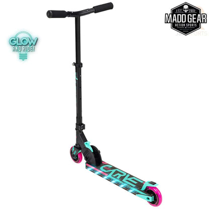 The Madd Gear MGP Carve Flight Light Up Foldable Scooter in teal and pink features a sleek design with a T-bar handle and adjustable handlebars, ideal for action sports. It has neon pink wheels, illuminating lights, and the vibrant "Glow and Ride!" text on the side. The Madd Gear logo is prominently displayed in the top right corner.