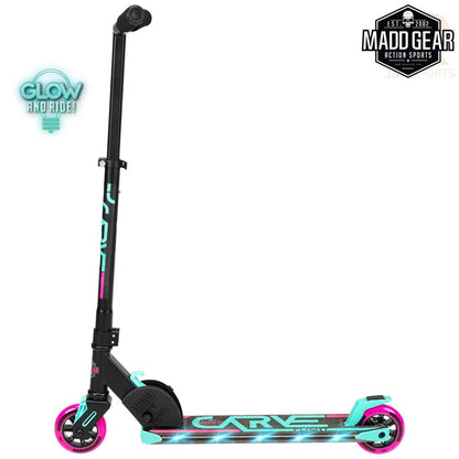 The Madd Gear MGP Carve Flight Light Up Foldable Scooter in teal and pink showcases sleek black and teal glowing wheels and deck with the word "Carve" prominently displayed on the side. Designed for exciting rides, this scooter includes a robust black T-bar handle. The "Madd Gear Action Sports" logo is prominently featured in the top right corner.