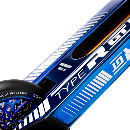 A close-up of the Root Industries Type R GT Complete Stunt Scooter in Blu-Ray reveals a blue deck adorned with white and blue geometric designs, prominently featuring "TYPE R GT." The design is further enhanced by a black wheel inscribed with "ROOT INDUSTRIES," highlighting this scooter as possibly the lightest pro offering from Root Industries.