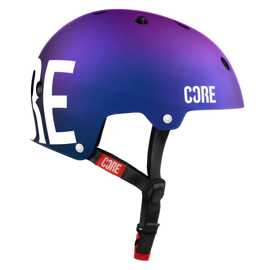 A side view of the CORE Street Skate/Scooter Helmet in a neo and white color gradient displays the brand name "CORE" prominently in large white letters on the side. This helmet is designed for street use and includes ventilation holes, along with an adjustable black strap featuring a red label that also reads "CORE.