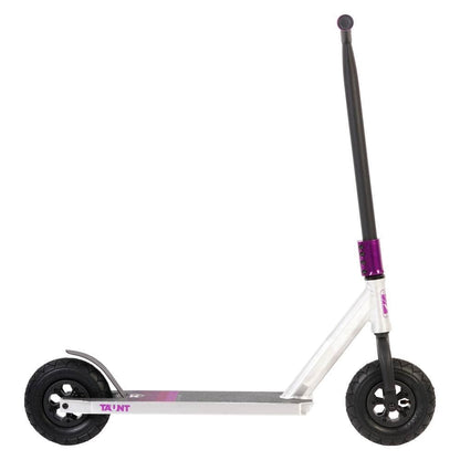 An angled perspective showcases the Invert Supreme Taunt Dirt Scooter in raw, pink, and purple hues. This model boasts a long handlebar, a fully integrated headset, large pneumatic wheels, a textured deck for added grip, and a reliable rear brake. The scooter is presented against a plain white backdrop.