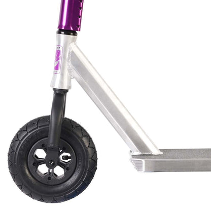 A close-up of the Invert Supreme Taunt Dirt Scooter - Raw / Pink / Purple showcases its front section with a silver frame and pneumatic black wheel. The handlebar stem is purple, adorned with an Invert branded sticker, and the deck features a metallic finish with a textured surface for grip. It includes a fully integrated headset for smooth steering and rugged adventures.