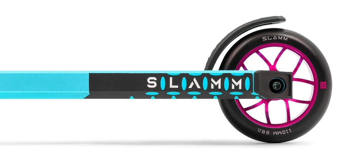 Close-up view of the rear wheel on the Slamm Assault Complete Stunt Scooter - Blue. This scooter features a striking blue and black color scheme, adorned with white "SLAMM" branding. It comes equipped with 110mm aluminum wheels, highlighted by a stylish pink and black wheel with a modern design, complemented by an integrated fender above it.