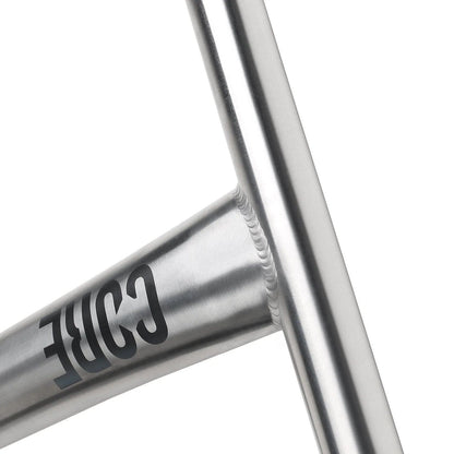 Close-up of a raw titanium scooter frame with a sleek, metallic finish. The CORE Nova V2 Titanium Oversized HIC Stunt Scooter Bars proudly display a stylized "CORE" logo. The image emphasizes the smooth welds and minimalist design admired by scooter enthusiasts.