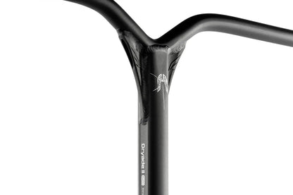 Close-up of black Ethic handlebars with a minimalist, smooth design. A subtle logo and the model name "Dryade V2" are visible on the vertical tube. The lightweight aluminium stunt scooter bars connect at a T-shaped intersection, highlighting a sleek, welded finish.