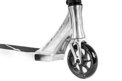 Close-up of the Ethic DTC Erawan V2 Complete Stunt Scooter in brushed silver, highlighting a detailed wheel and intricately engraved metallic frame. The visible fork showcases IHC compression, with a deck inspired by the Ethic Erawan V2's distinctive designs, emphasizing the scooter's modern and stylish appearance.