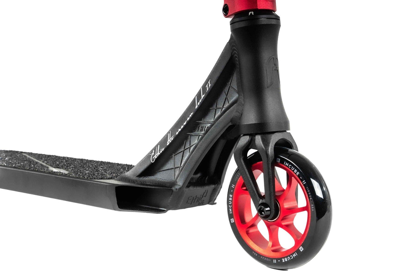 A close-up of the Ethic DTC Erawan V2 Complete Stunt Scooter showcases its black deck paired with a red wheel. This complete scooter features a textured surface, lattice design on the side, and IHC compression system for smooth rides.