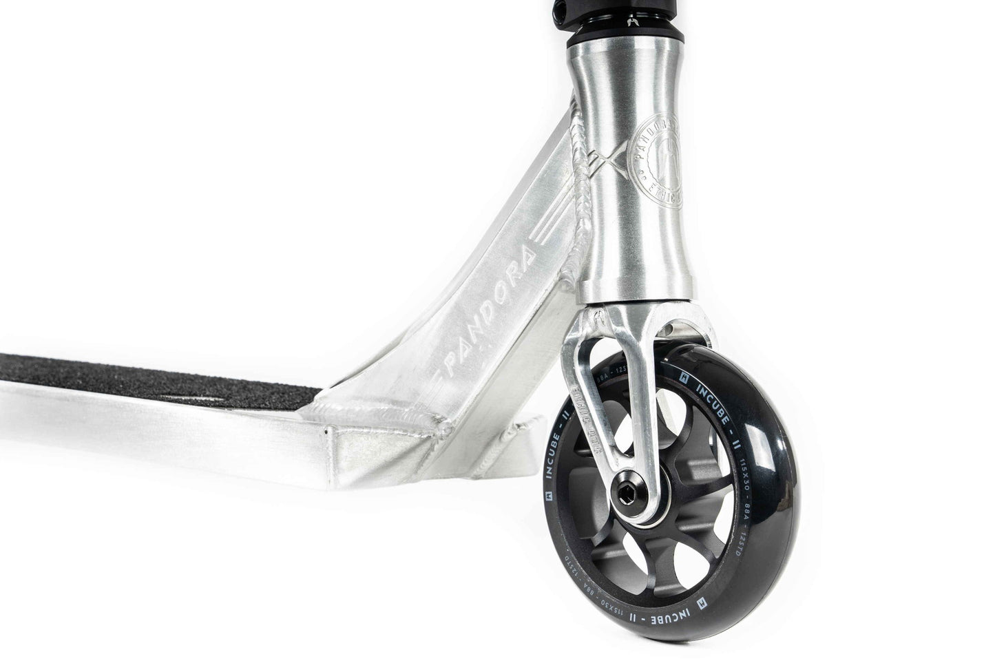 Close-up of the front wheel and deck of an Ethic DTC Pandora Complete Stunt Scooter in Brushed Silver. The black wheel features silver spokes and is labeled "110mm." The deck is covered with grip tape for stability during street riding. A chromoly steel T-bar enhances durability, while the brand name "Pandora" is boldly displayed on the frame.