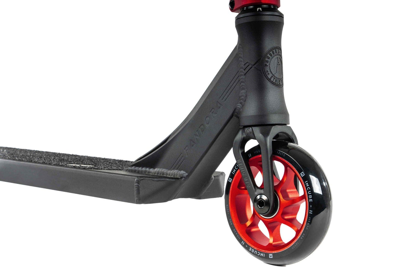 Close-up of the Ethic DTC Pandora Complete Stunt Scooter's front wheel and deck in sleek black and red. The vivid red core contrasts beautifully with the black outer rim, and its textured deck enhances grip. Its modern design features a chromoly steel T-bar, perfect for street riding. The word "Pandora" is emblazoned on its frame.