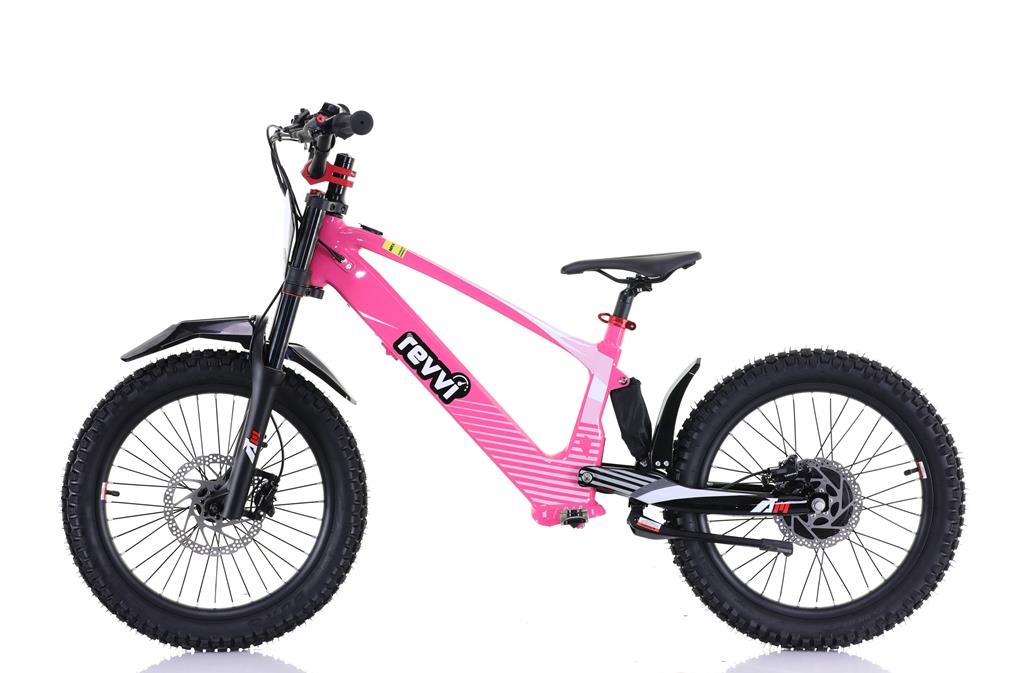 Side view of the Revvi 20" Kids Electric Balance Bike in bright pink features thick tires, speed settings, a black saddle, robust front suspension, and disc brakes. The bike's frame displays the Revvi brand name and is isolated on a white background.