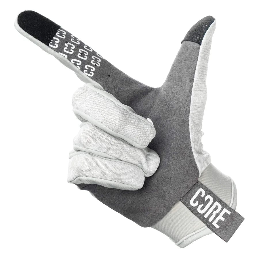 Introducing the CORE Aero Skate Protection Gloves - Kieran Reilly Signature White, these gloves enhance grip functionality with their gray and white design complemented by a black index fingertip. The glove is styled in a manner that mimics a finger gun gesture, further distinguished by the word "CORE" prominently displayed on the wristband.