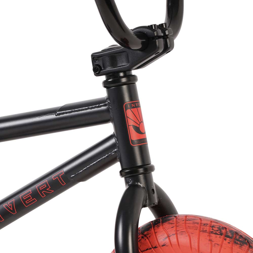 Close-up of the Invert Supreme Havoc Mini BMX bike frame in black with red detailing, showcasing the brand name "Invert" and a logo on the head tube. The handlebars and part of the front wheel with marble tires are also visible, making it ideal for action sports enthusiasts.