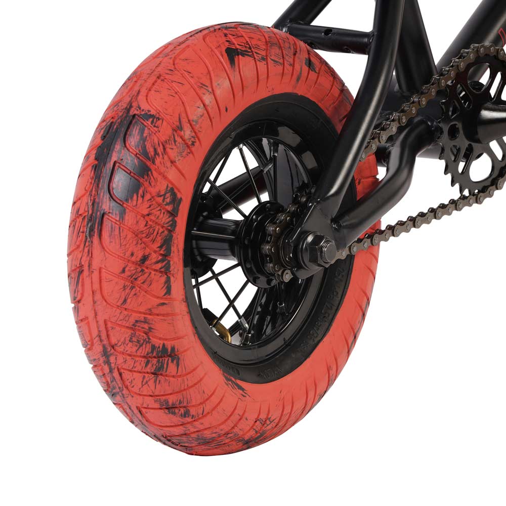 A close-up of the Invert Supreme Havoc Mini BMX Bike showcases a red, used tire with visible dirt and chain links, capturing the spirit of action sports. The black frame suggests recent use. The image highlights the rear wheel and part of the drivetrain, evoking Mini BMX builds.