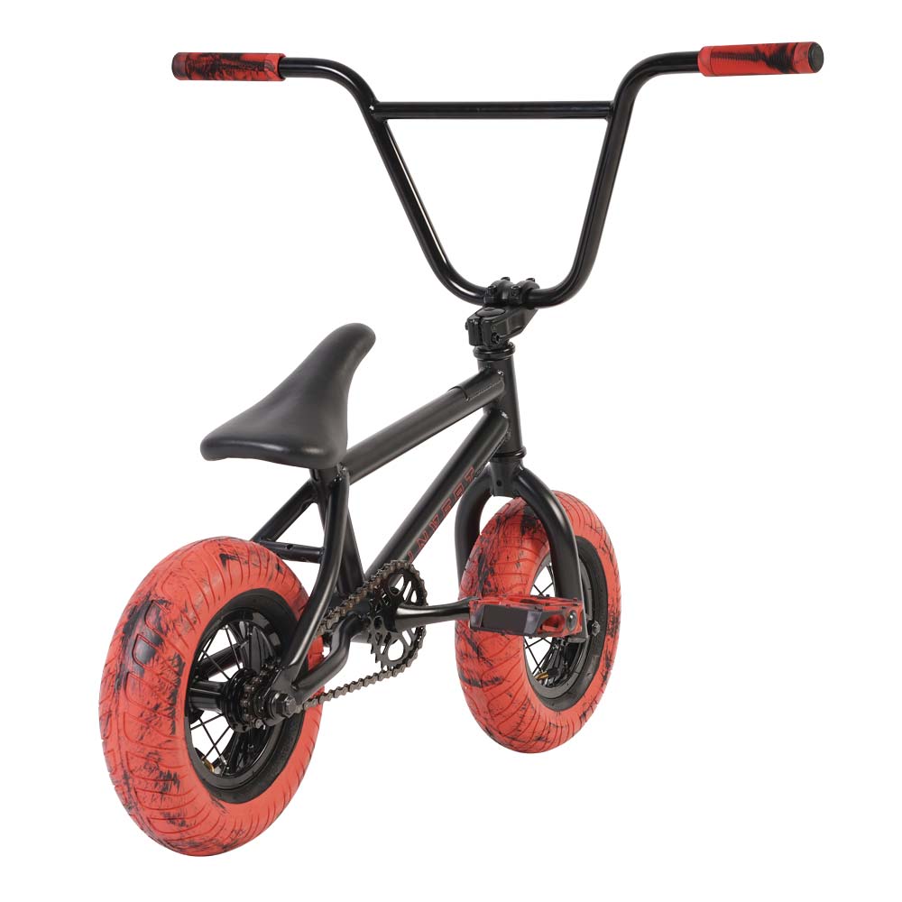 An Invert Supreme Havoc Mini BMX Bike in black with striking red marble-patterned tires and coordinating red handlebar grips. Photographed from a rear perspective, it highlights its compact frame and robust construction, making it ideal for action sports enthusiasts.