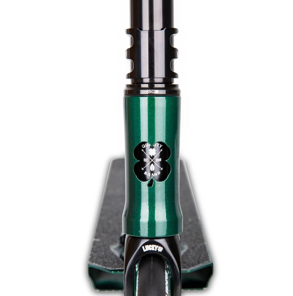 Close-up view of the Lucky Covenant 2021 Complete Stunt Scooter in Emerald Green, featuring a clover logo on the front fork. The scooter deck, known for its textured grip surface, is predominantly black. The image highlights the connection between the front wheel and handlebar.