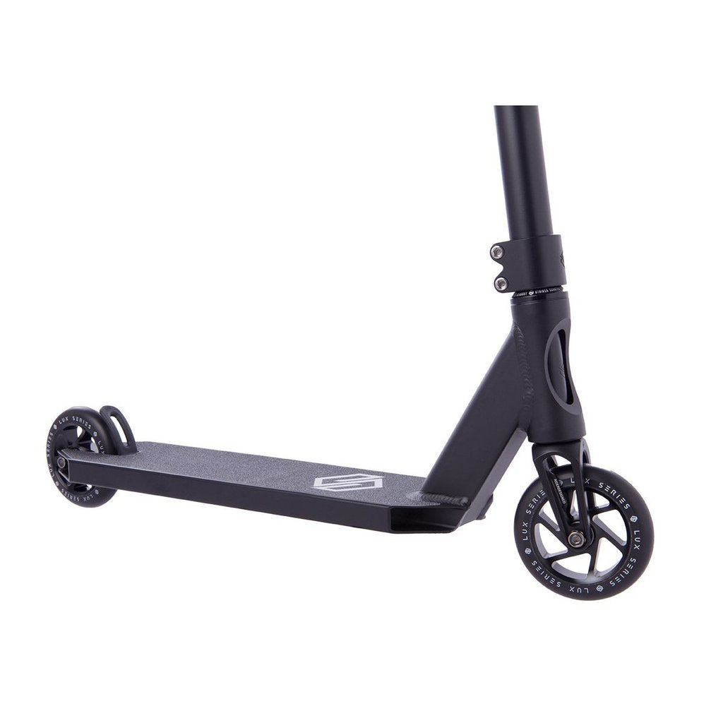 The Striker Lux Pro Complete Stunt Scooter in black, from the Striker brand, is a lightweight kick scooter featuring two small wheels and an aluminum deck with a minimalistic design and logo. Its partially visible handlebars add to its sleek, modern look, making it ideal for urban commuting or recreational use.