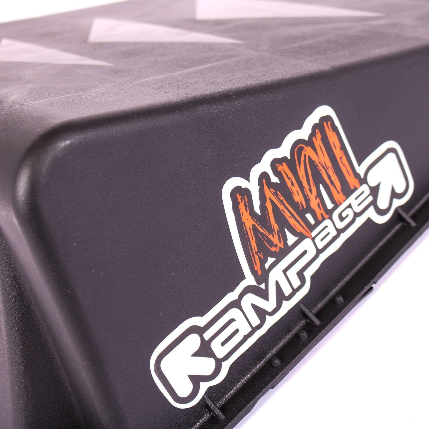 Close-up of a black Rampage Single Mini Launch Skate Ramp featuring a white and orange "Rampage" logo on the side. Ideal for skating and scootering enthusiasts, its surface includes subtle triangular patterns for enhanced grip.